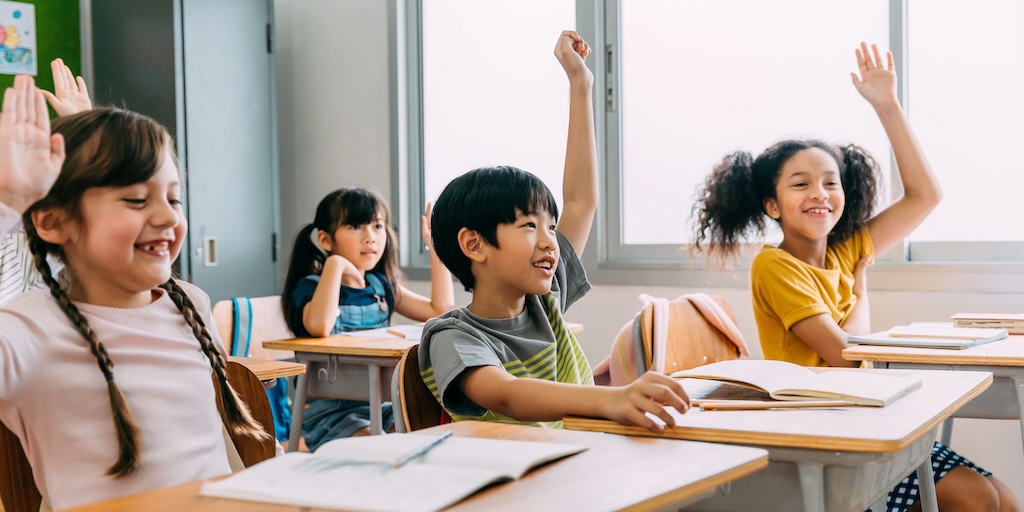 elementary kids raising hands in class