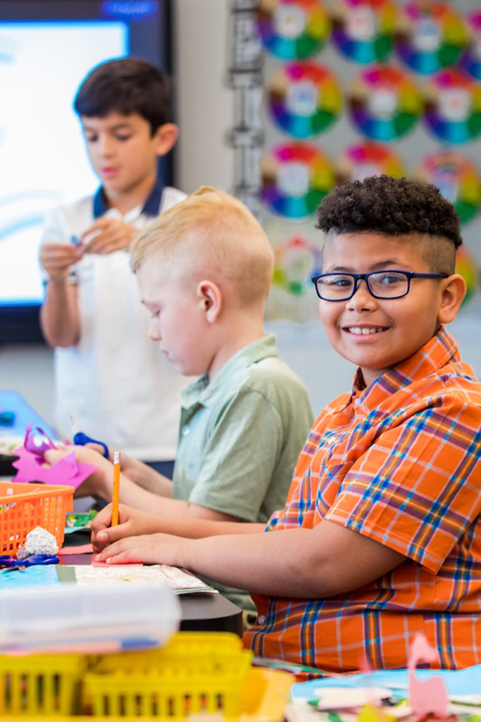 boy with glasses smiling at camera in classroom boy with glasses smiling at camera in classroom